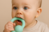 A baby holding a teething ring, with a soft and soothing background, symbolizing comfort during teething.